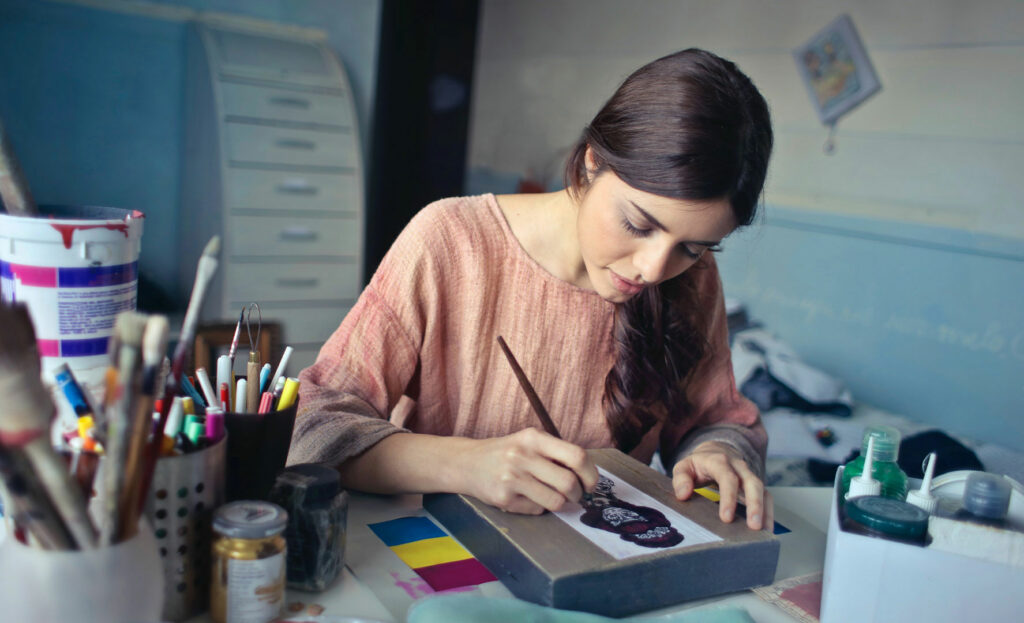Frau malt auf einem Blatt Papier mit Pinsel